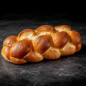 A braided challah loaf on a dark surface